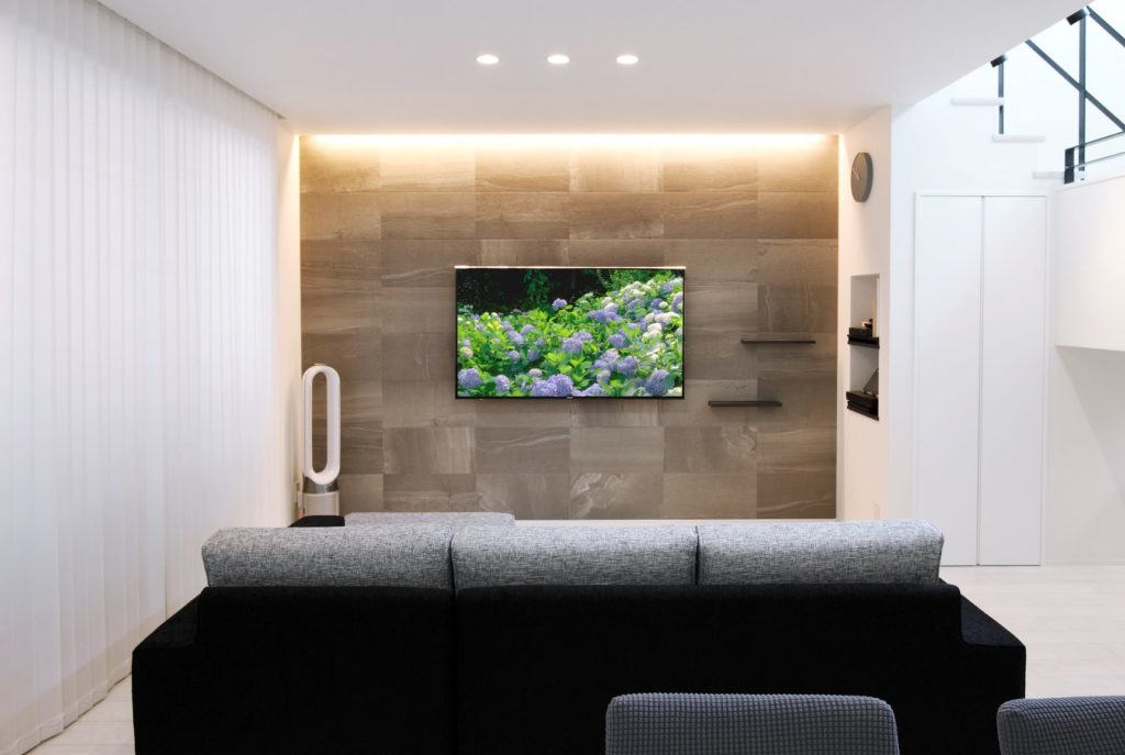床や壁を白くすることで、テレビをつけたグレーのタイルと間接照明が際立つ
