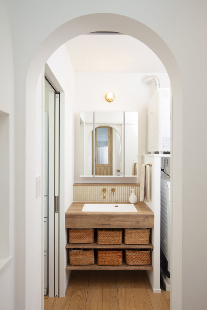 洗面室もホワイト×木×真鍮でコーディネート。タイル張りやマリンランプがかわいい。